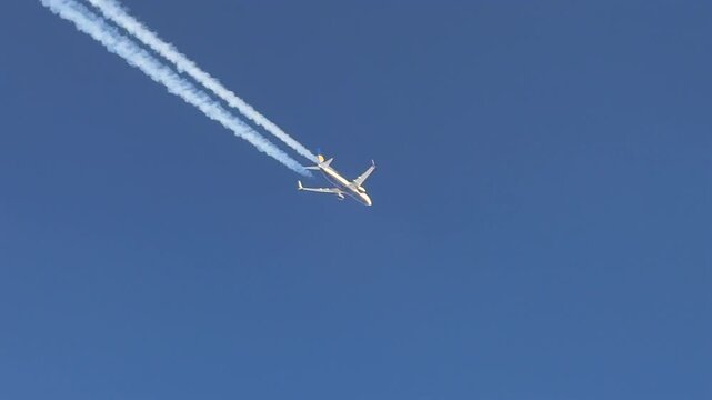 Cockpit view of a twin-engine jet and its fading contrail flying in a blue sky, crossing the screen in diagonal. captured from another cockpit flying same track 600m bellow.