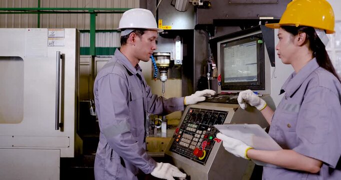 Asian technician and woman engineer review CNC control panel beside machine, checking program setting, spindle area, safety step, production status, digital workflow coordination in .