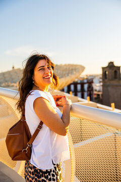 Travel, tourism: Smiling woman looks at the view from Metropol Parasol, la Setas, Seville, Spain, enjoying the sunset and the city landscape.