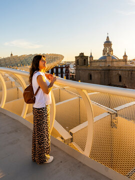 Travel, tourism: Woman looks at the cityscape from Metropol Parasol during sunset, enjoying the view and the lifestyle in Seville, Spain.
