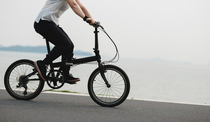 Naklejka premium Riding folding bike on seaside road