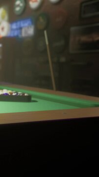 A group of friends prepares to play billiards on a green felt pool table. The balls are arranged in a triangle at one end of the table. The setting is casual and warm.