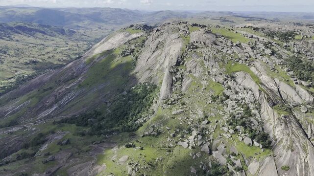 Drone orbits to right on south side of cliff face on a sunny day at Sibebe Rock near Mbabane, Eswatini