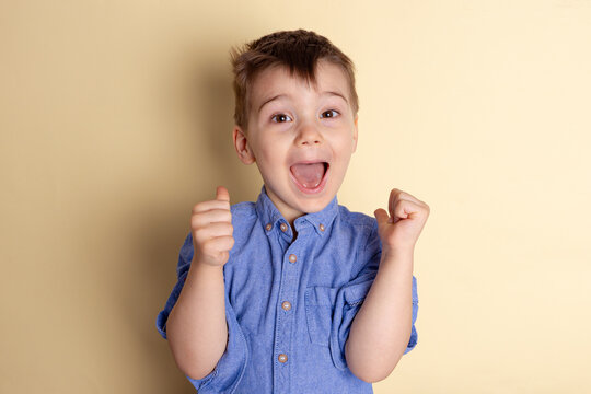 Boy of three years in a blue shirt on a yellow background. Emotional portrait.