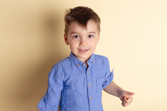 Boy of three years in a blue shirt on a yellow background. Emotional portrait.
