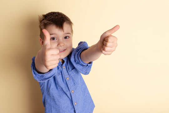 Boy of three years in a blue shirt on a yellow background. Emotional portrait.