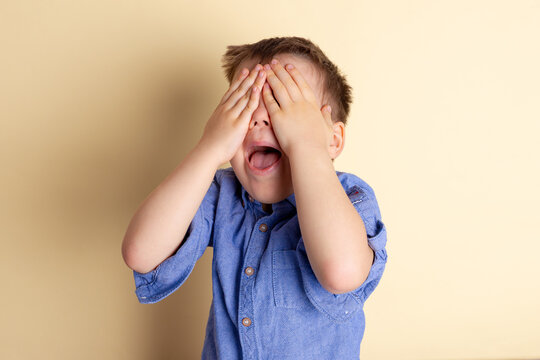 Boy of three years in a blue shirt on a yellow background. Emotional portrait.