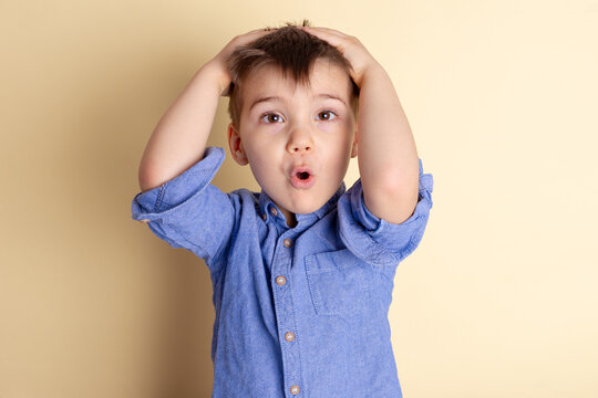 Boy of three years in a blue shirt on a yellow background. Emotional portrait.