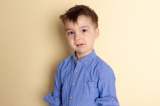 Boy of three years in a blue shirt on a yellow background. Emotional portrait.