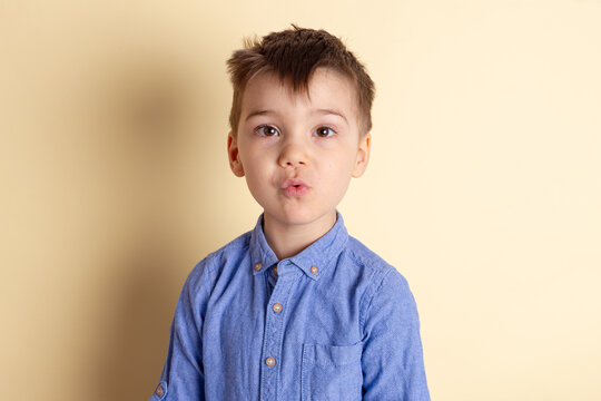 Boy of three years in a blue shirt on a yellow background. Emotional portrait.