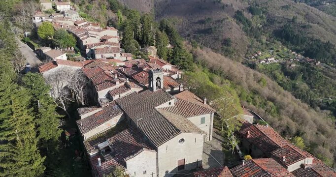 Aerial view of the historic village of Trappola with its stone bell tower and red-tiled rooftops nestled in the green hills of the Pratomagno area Trappola, Tuscany, Italy.