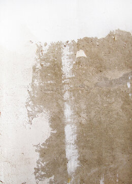 Wall surface with visible plaster and filler stains before painting. Uneven patches and textures highlight preparation stage in interior renovation work.