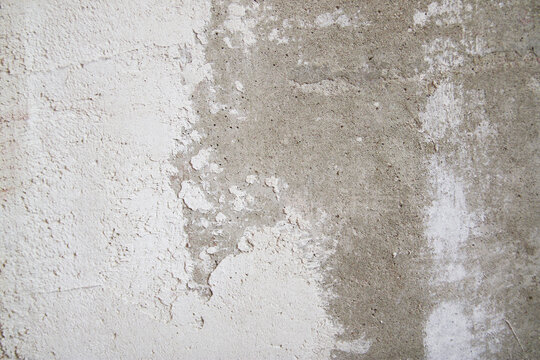 Close-up of uneven wall texture with spackle stains and plaster layers. Minimal composition reflects renovation workflow and surface correction.