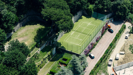 Tennis court in camogli, italy, seen from above, showing surrounding vegetation and parking lot © Doralin