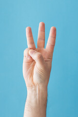 Naklejka premium Hand showing three finger gesture against blue background