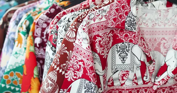Colorful elephant patterned shirts hanging on rack, Hawaii shirt, representing Asian fashion, Thai traditional textile design, cultural identity, retail display, and clothing industry concept