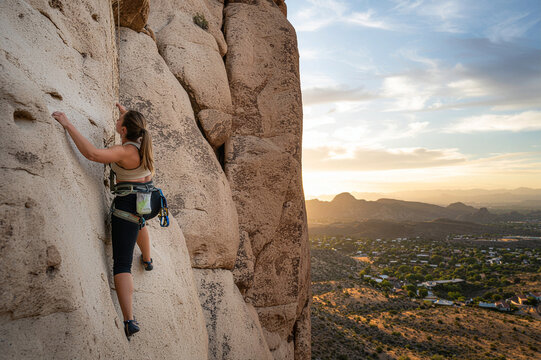Rear view of female hiker rock climbing against cloudy sky, adventure and challenge concept
