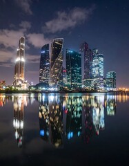 Naklejka premium A nighttime cityscape with modern skyscrapers reflected in water