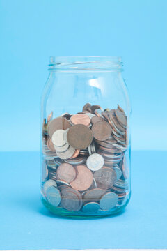 Close-up of a glass jar three quarters full of assorted UK coins