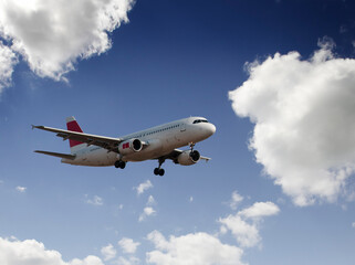 Commercial airplane flying in blue sky with clouds passenger jet landing travel aviation concept © madedee