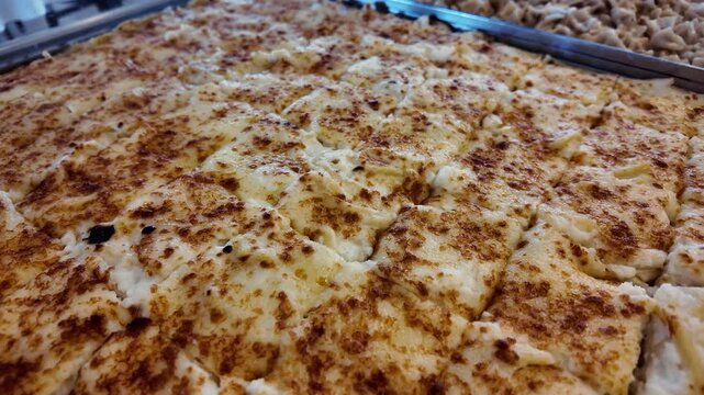 Close-up macro view of freshly baked pasta with creamy bechamel sauce and golden cheese crust. Traditional Turkish style "Fırın Makarna" served in a tray, showing crispy texture and melted cheese.