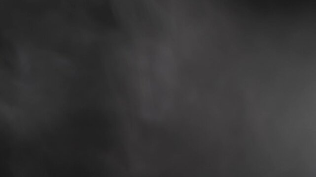 White smoke drifts and swirls slowly from left to right across a black screen. Ethereal vapor creates a mysterious and atmospheric texture against the dark background.