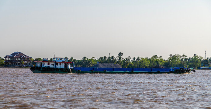 A view of a coal cargo barge on the Hau river near Can Tho in the Mekong Delta, Vietnam on a bright sunny day