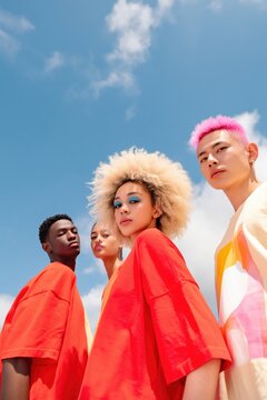 Four diverse models standing under partly cloudy blue sky