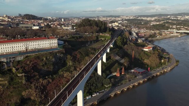 Aerial view of the Maria Pia Bridge spanning the Douro River, with the city skyline in the distance, reflecting the urban landscape, Porto, Portugal.