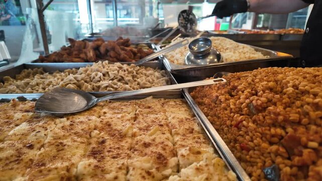 Traditional Turkish tradesman restaurant buffet with various hot dishes, baked pasta, manti, rice and bulgur pilav. Authentic local eatery food service in metal trays, delicious homemade cuisine.