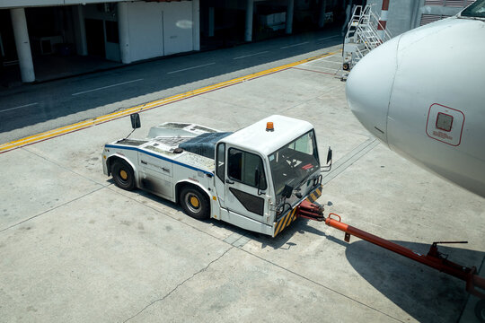 View of an aircraft tug with its arm attached to an aircraft on the tarmac of an airport