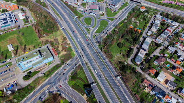Aerial view of a bustling highway intersection cutting through green spaces and buildings, a symphony of concrete and nature, Prague, Prague, Czechia.