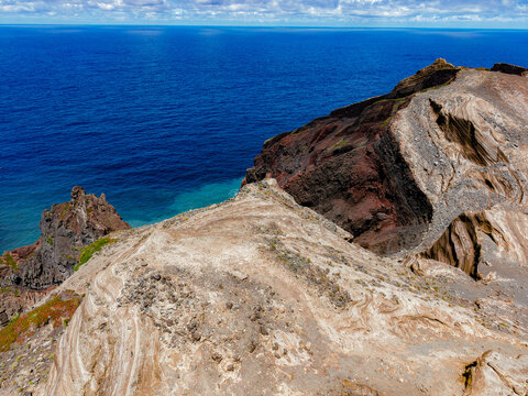 Aerial view of the volcanic landscape where the dark cliffs dramatically meet the deep blue sea, Capelo, Acores, Portugal.