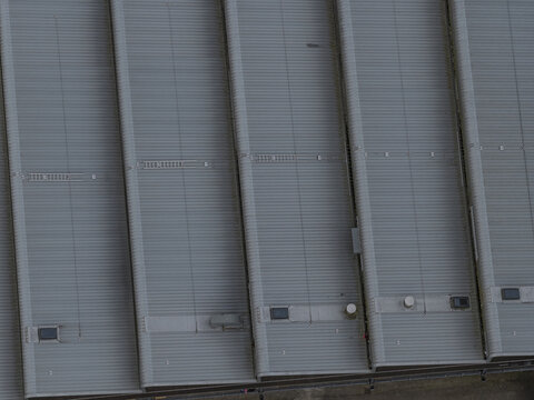 Aerial view of the corrugated metal sawtooth roof of a large industrial building with parallel sections and vents Leccio, Tuscany, Italy.