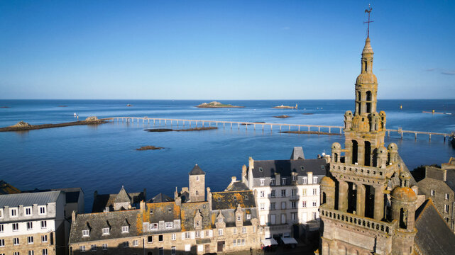 Aerial view of the old church steeple towers over the quaint town, leading the eye to the expansive ocean and distant islands, Roscoff, Bretagne, France.