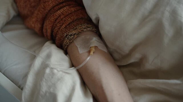 Hand with attached IV drip or cannula receiving fluids