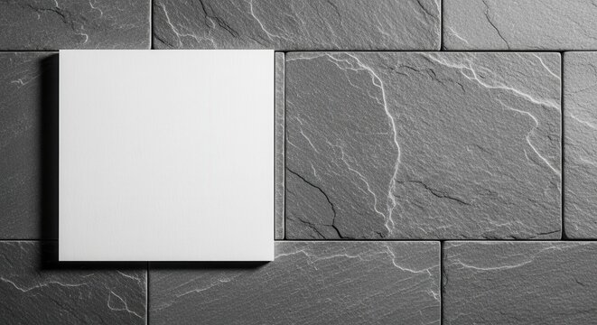 A crisp white square sheet precisely aligned on a textured gray stone tile surface, offering a clean and modern contrast.