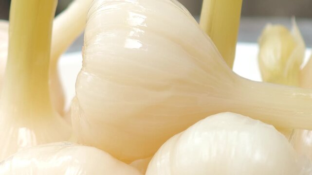 Garlic pickled in syrup in a container.