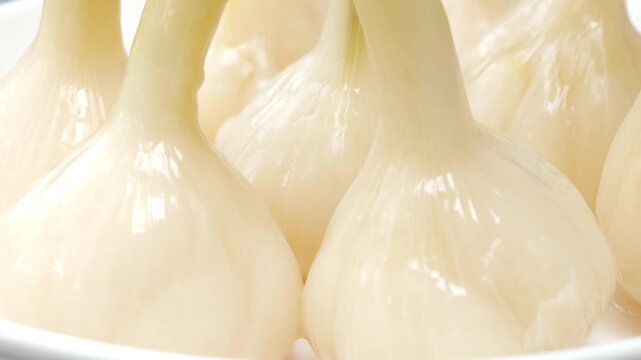 Garlic pickled in syrup in a container.