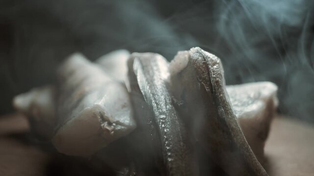 Detailed view of frozen raw hake fish carcasses emitting cold smoke on a dark background. Concept of modern seafood preservation, deep freezing technology, and culinary preparation.
