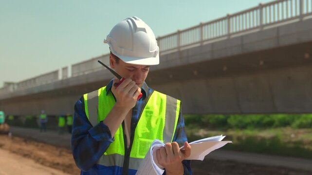 Construction engineer hard hat safety vest bridge worker site outdoor daylight civil, construction worker safety helmet and reflective vest using walkie talkie bridge site with blueprint hand