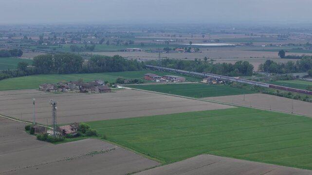 Trenitalia Frecciarossa high speed passenger train running parallel to Autostrada A1 near Fiorenzuola d Arda Piacenza Emilia Romagna Italy within Milan Bologna rail corridor, drone tracking