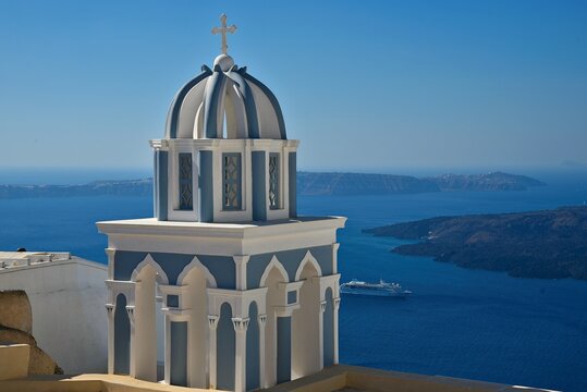 Landscape with scenic view of the Neo-Baroque bell tower of St. John the Baptist Catholic Cathedral overlooking the caldera in Fira, Santorini island, Greece.