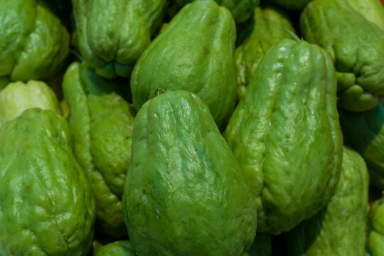 Fresh green chayote stacked in close-up. Smooth, ridged skin reflects natural light. Perfect for cooking, salads, or healthy food content. Ideal for culinary, nutrition, or market visuals