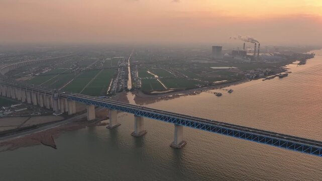 The Shanghai-Suzhou-Nantong Yangtze River Bridge at sunset, with the distant scenery of the steel industrial base in the background
