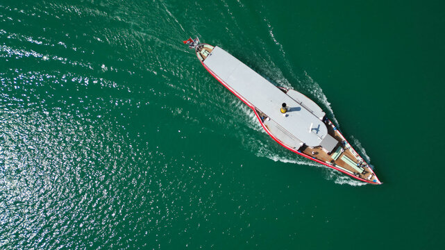 Aerial view of a vintage boat sailing across the serene waters of Lake Neuchatel, the vessel's red trim sharply contrasting with the deep green of the lake, Neuchatel, Neuchatel, Switzerland.