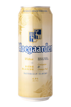 A tall can of Hoegaarden wheat beer sits upright. The can features a simple design with a light color. It includes notes about ingredients like coriander and orange peel