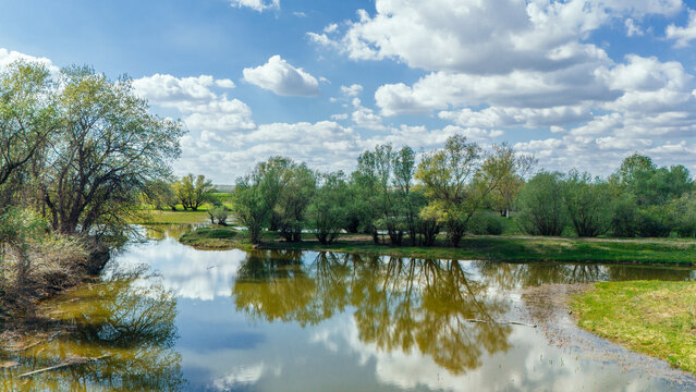 Aerial view of serene waters reflecting the sky and trees, with patches of green and brown earth adding texture to the landscape, Kovilj, Vojvodina, Serbia.