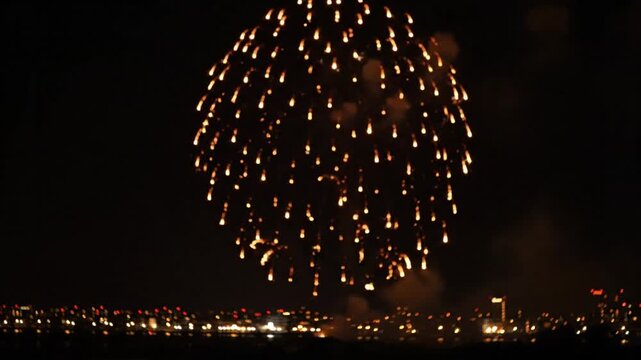 Spectacular golden fireworks display exploding over a dark city skyline during a nighttime celebration