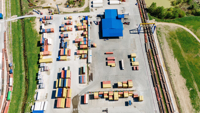 Aerial view of a vibrant container yard with rows of colorful containers, adjacent to a railway line, contrasting against the green surroundings, Sremska Mitrovica, Vojvodina, Serbia.